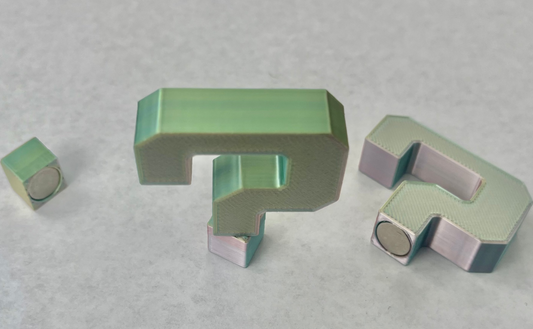 A set of green magnetic hat brim accessories arranged in a question mark formation on a grey surface.
