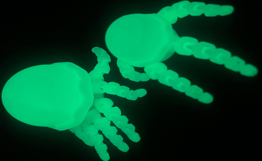 Two green jellyfish-shaped objects glowing in the dark on a black background