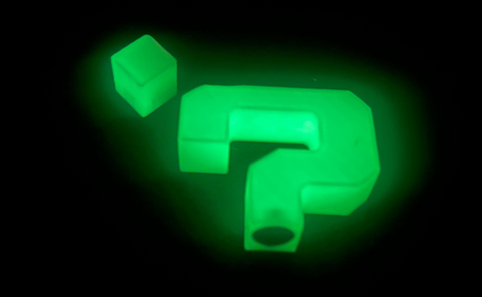 Glowing green plastic components on a black background