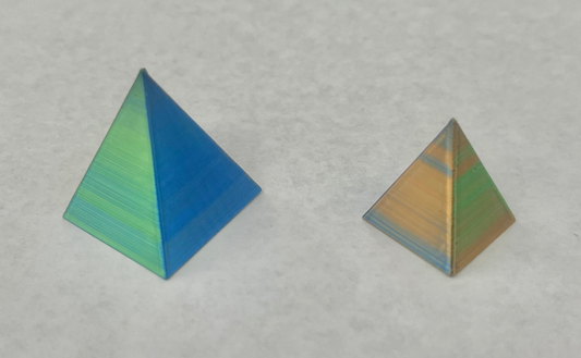 Two geometric pyramids with a magnetic interaction, one is blue at the base and green at the top, the other is orange at the base and green at the top.