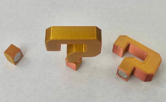 Magnetic hat brim accessories in the shape of a question mark, with a metallic gold finish.