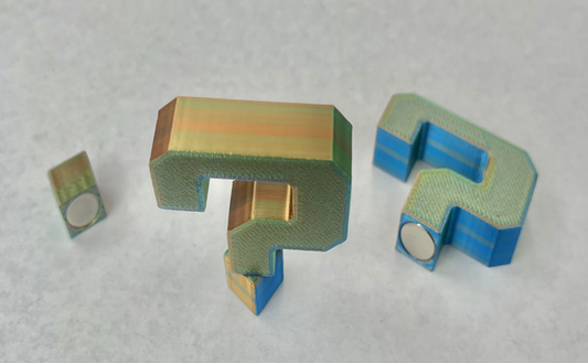 Magnetic question mark-shaped accessory in gold and blue colors, designed for use with hats.